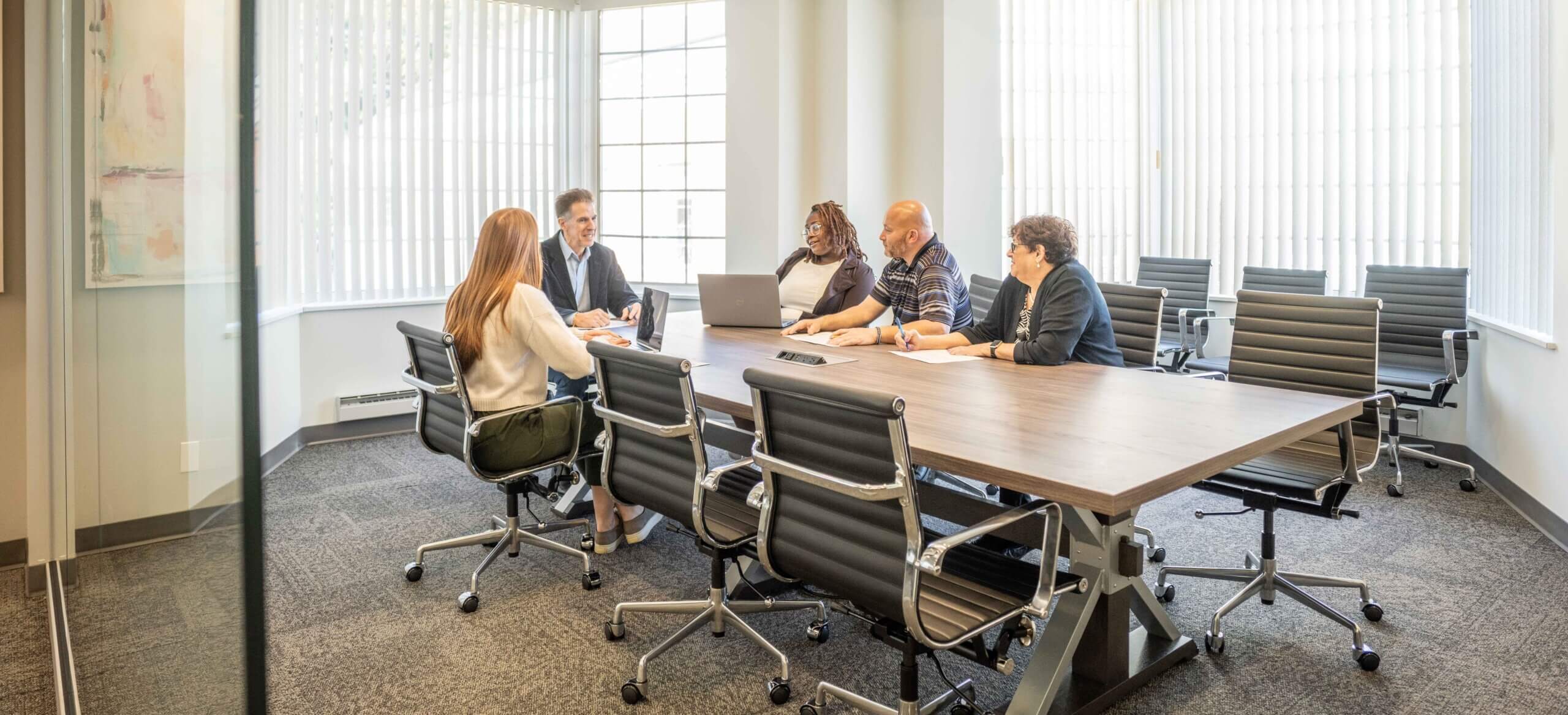 Employees sitting at conference room table talking to each other