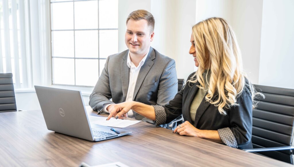 Two coworkers sitting at desk looking at computer