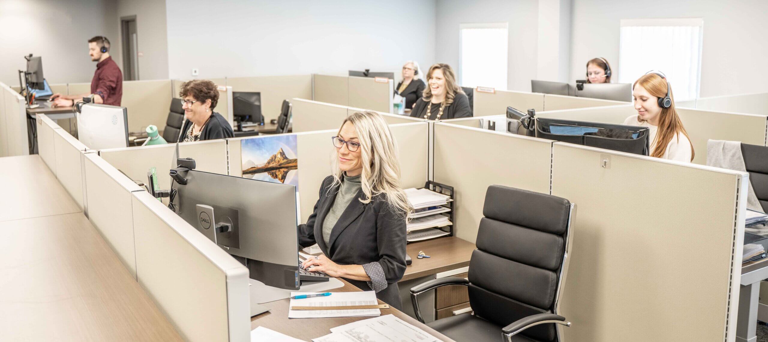 Encore employees sit inside their individual cubicles and work on Payroll Funding for Staffing Companies.